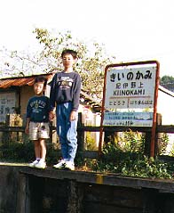 駅名板をバックに
